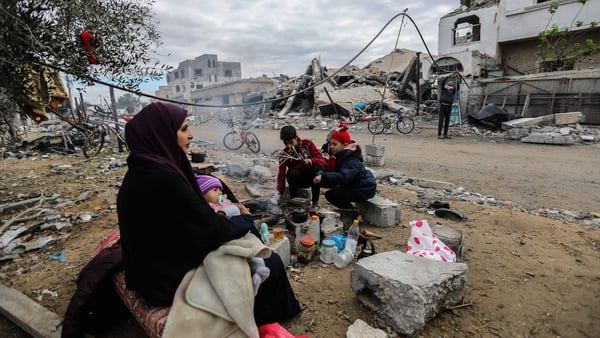 A woman sits with her children amid the ruins of nearby buildings in Gaza